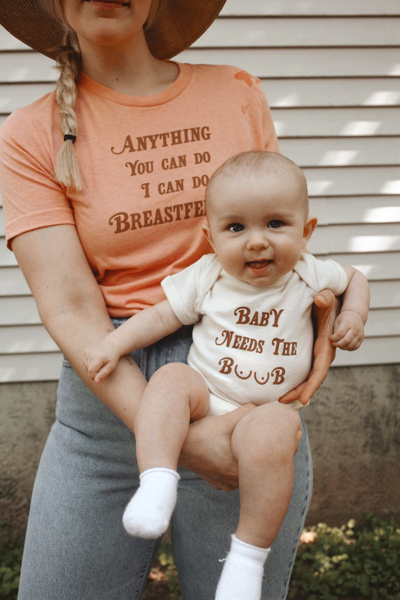 Mother holding baby that is wearing a funny baby onesie