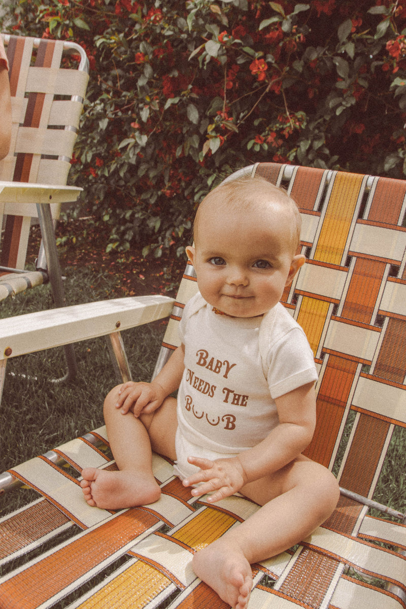 Cute baby sitting in a vintage chair wearing a funny baby onesie